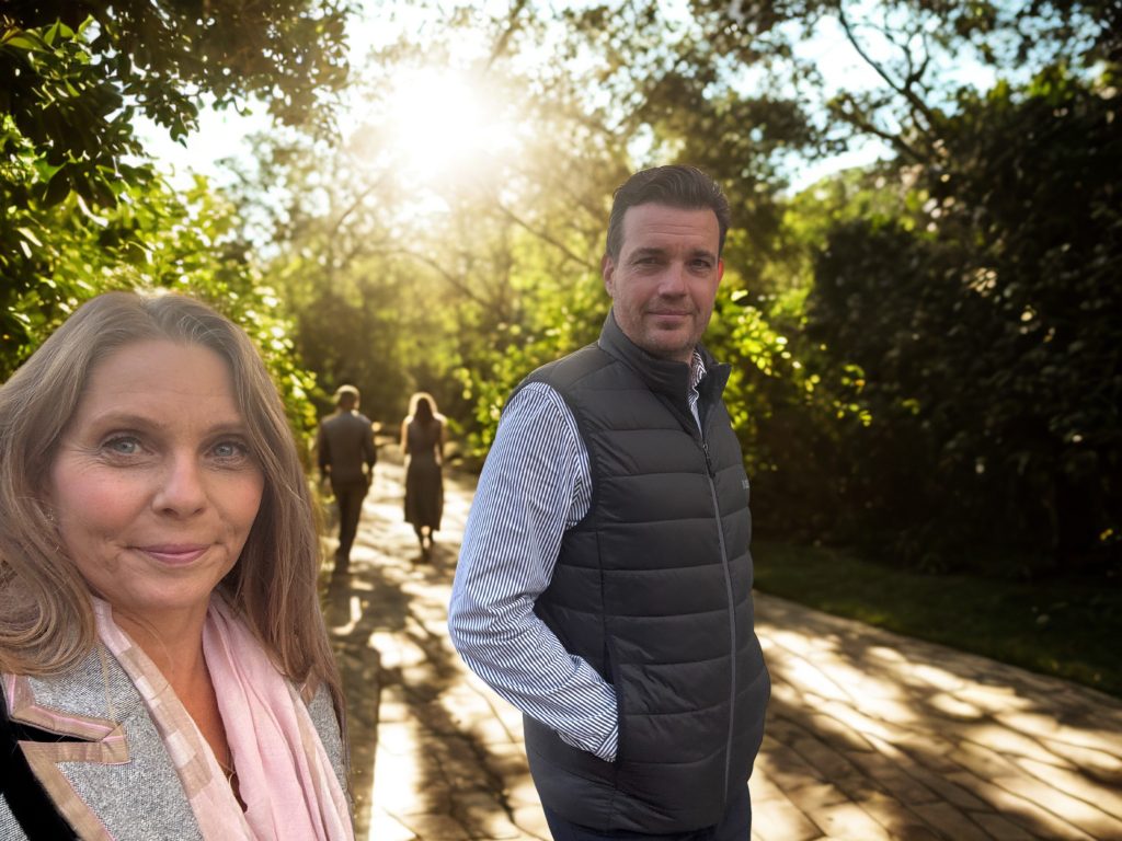 Heidi og Martin Riishøj udendørs på en sti med solskin gennem træerne.
